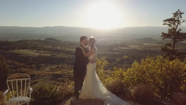 A bride and groom sharing a kiss on a scenic mountain overlook during golden hour.