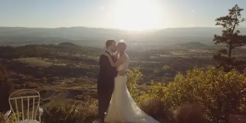 A bride and groom sharing a kiss on a scenic mountain overlook during golden hour.
