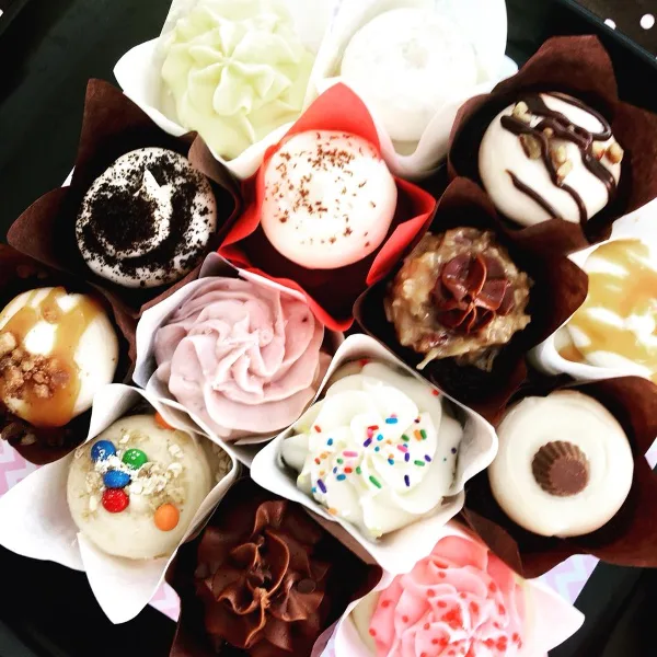 A collection of assorted decorated cupcakes in paper liners.