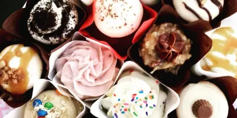 A collection of assorted decorated cupcakes in paper liners.