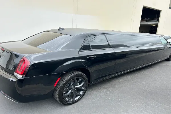 Black stretch limousine parked on pavement in front of a building