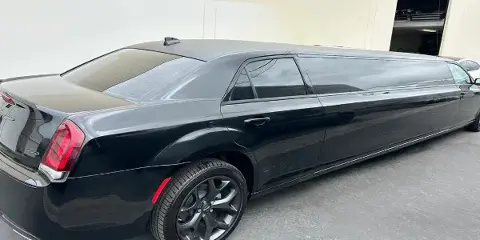 Black stretch limousine parked on pavement in front of a building