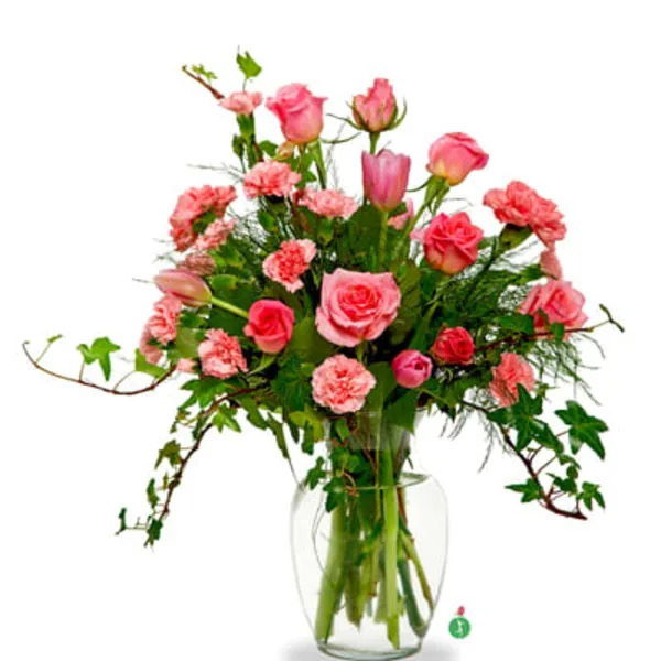 A floral arrangement featuring pink roses, carnations, and greenery in a clear glass vase.