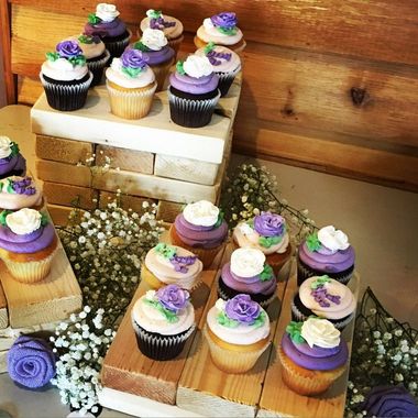 A display of decorated cupcakes with purple and white frosting arranged on wooden crates.