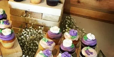 A display of decorated cupcakes with purple and white frosting arranged on wooden crates.