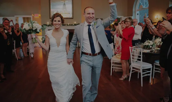 A bride and groom dancing at a wedding reception while guests applaud in the background.