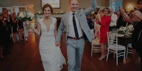 A bride and groom dancing at a wedding reception while guests applaud in the background.