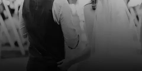 A black and white photograph of a bride and groom standing together at a wedding ceremony.