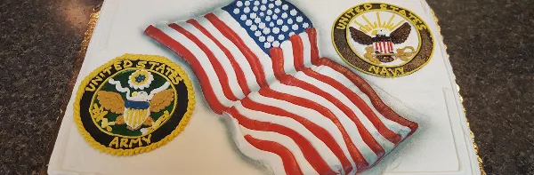 A white frosted cake decorated with a 3D American flag and military patches for the US Army and US Navy.