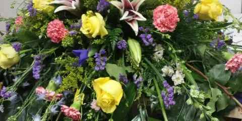 Large mixed floral arrangement with yellow roses, lilies, and pink carnations