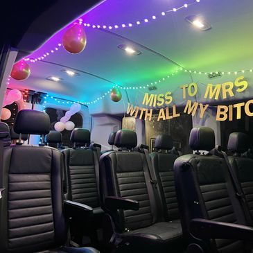 Interior of a passenger van decorated with string lights and a wedding banner.