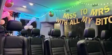 Interior of a passenger van decorated with string lights and a wedding banner.