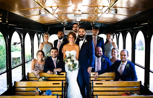 A wedding party posing inside a vintage-style trolley car.