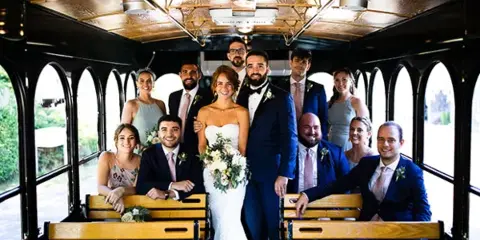 A wedding party posing inside a vintage-style trolley car.