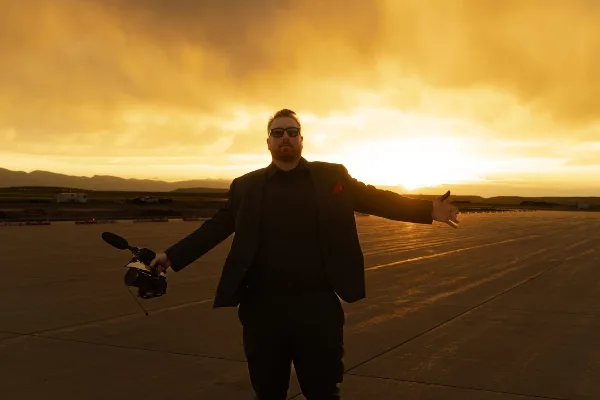 Mike Ask, founder of Coach Mike Entertainment, holding a wireless microphone at sunset.