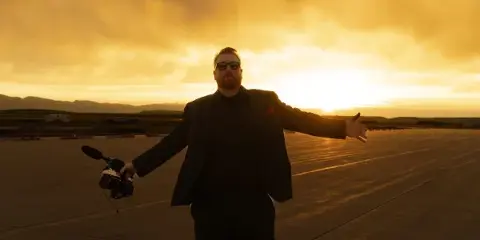 Mike Ask, founder of Coach Mike Entertainment, holding a wireless microphone at sunset.
