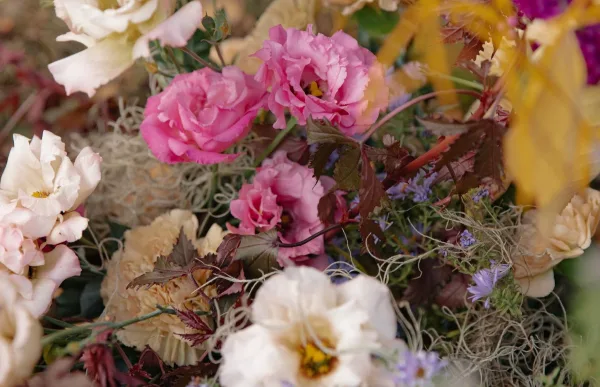 Close-up of a floral arrangement with pink and white roses, dahlias, and greenery.