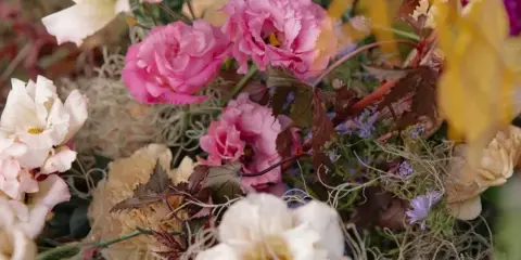 Close-up of a floral arrangement with pink and white roses, dahlias, and greenery.
