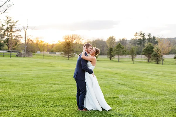 A bride and groom embracing on a green lawn during a wedding photoshoot.
