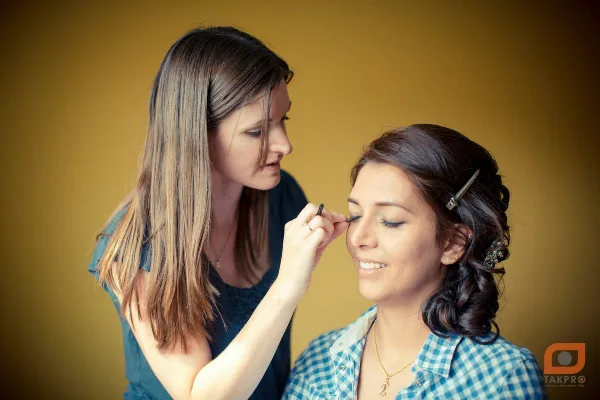 A makeup artist applying makeup to a client's face in a studio setting.