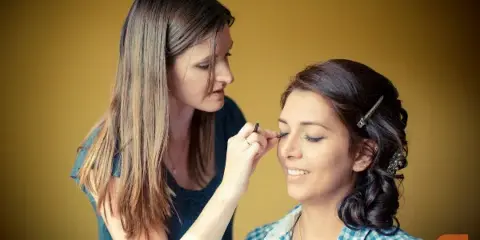A makeup artist applying makeup to a client's face in a studio setting.