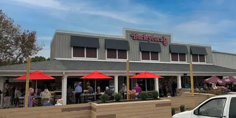 Exterior view of a Barleycorn's restaurant with red patio umbrellas and outdoor seating.