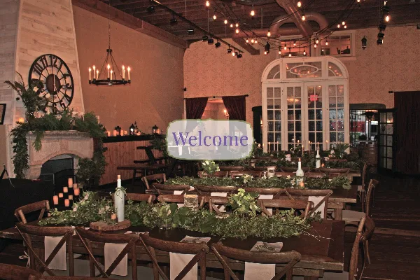 A rustic wedding reception hall with long wooden tables, floral centerpieces, and string lighting.