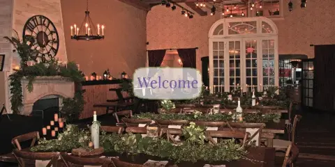 A rustic wedding reception hall with long wooden tables, floral centerpieces, and string lighting.