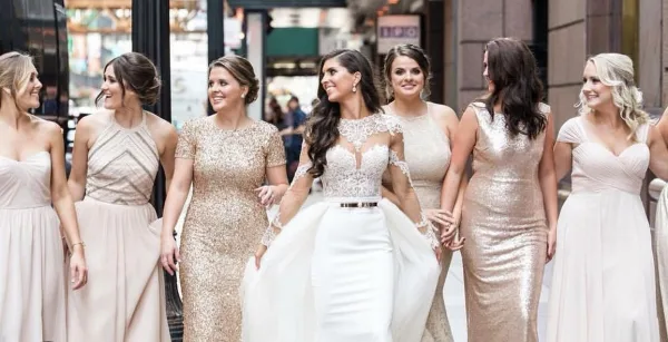 A bride and her bridesmaids walking together, showcasing professional wedding hair and makeup.