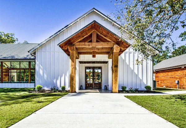 Exterior view of a white wedding venue chapel with a wooden entryway and covered porch.