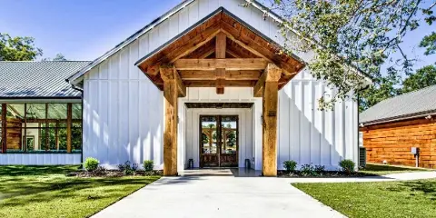 Exterior view of a white wedding venue chapel with a wooden entryway and covered porch.