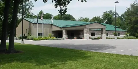 Exterior view of the Wells County 4-H Park Community Center building with a green roof and stone facade.
