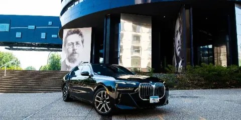 Black luxury sedan parked in front of a modern building