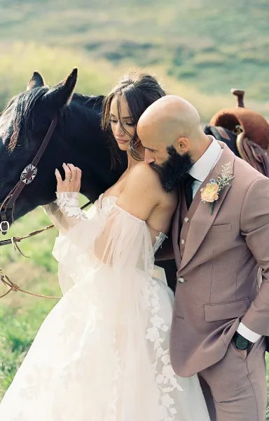 Wedding couple embracing outdoors next to a horse