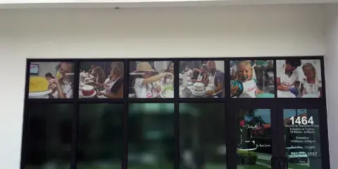 Exterior storefront of a cake shop with a 'Make it Swirl' sign and window displays showing people decorating cakes.