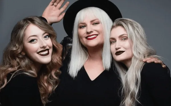 Three women posing together in a studio setting, showcasing professional hair styling and makeup.