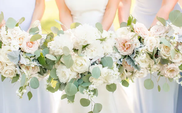 Close-up of a white and blush floral arrangement with eucalyptus held by bridesmaids.