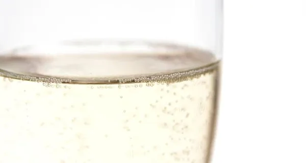 Close-up of a glass of champagne with bubbles against a white background.