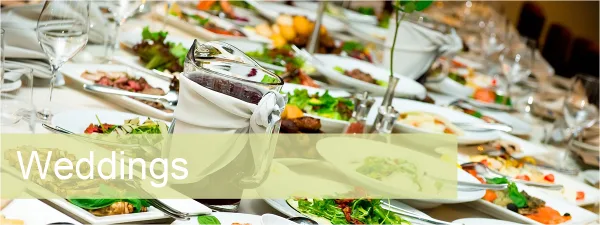 A long banquet table set with white plates, wine glasses, and various plated food dishes.