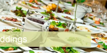 A long banquet table set with white plates, wine glasses, and various plated food dishes.