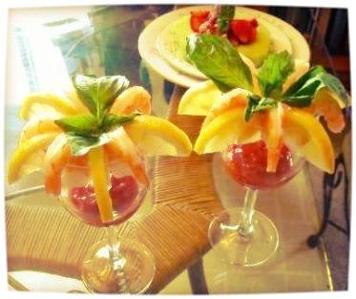 A close-up of a shrimp cocktail appetizer garnished with fruit and mint leaves.
