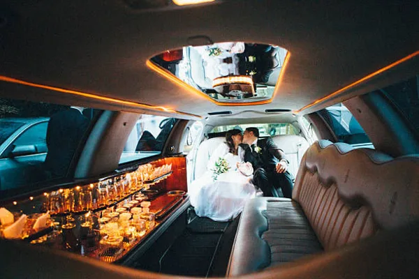 Interior view of a luxury limousine with a bride and groom seated in the back.