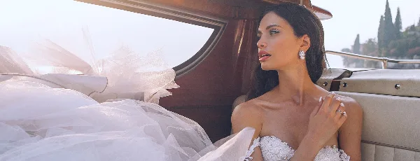 A bride in a white wedding dress sitting in a boat.