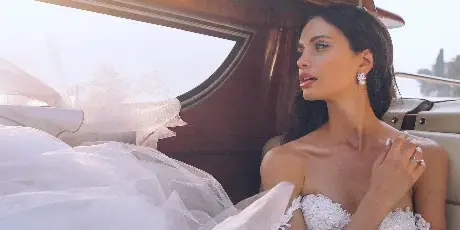 A bride in a white wedding dress sitting in a boat.