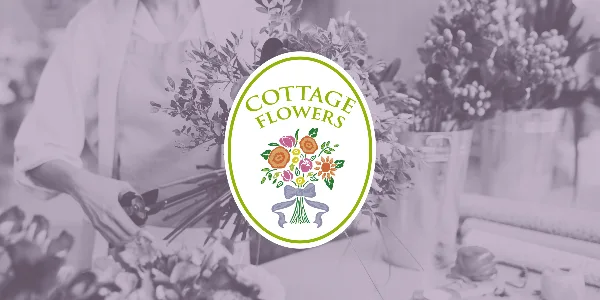 A florist arranging a bouquet of flowers in a studio setting with buckets of stems in the background, overlaid with the Cottage Flowers logo.