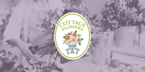 A florist arranging a bouquet of flowers in a studio setting with buckets of stems in the background, overlaid with the Cottage Flowers logo.