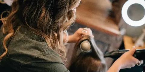 A stylist blow-drying and styling a client's hair with a round brush in a salon.