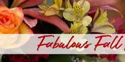 A close-up photograph of a vibrant floral arrangement featuring orange roses, pink lilies, and yellow alstroemeria.