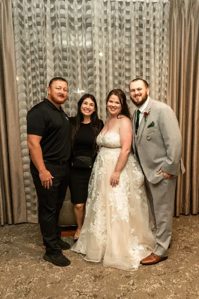 A bride and groom posing with two wedding planners in a decorated venue.
