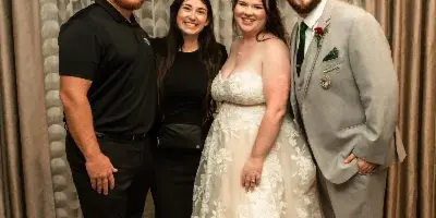A bride and groom posing with two wedding planners in a decorated venue.